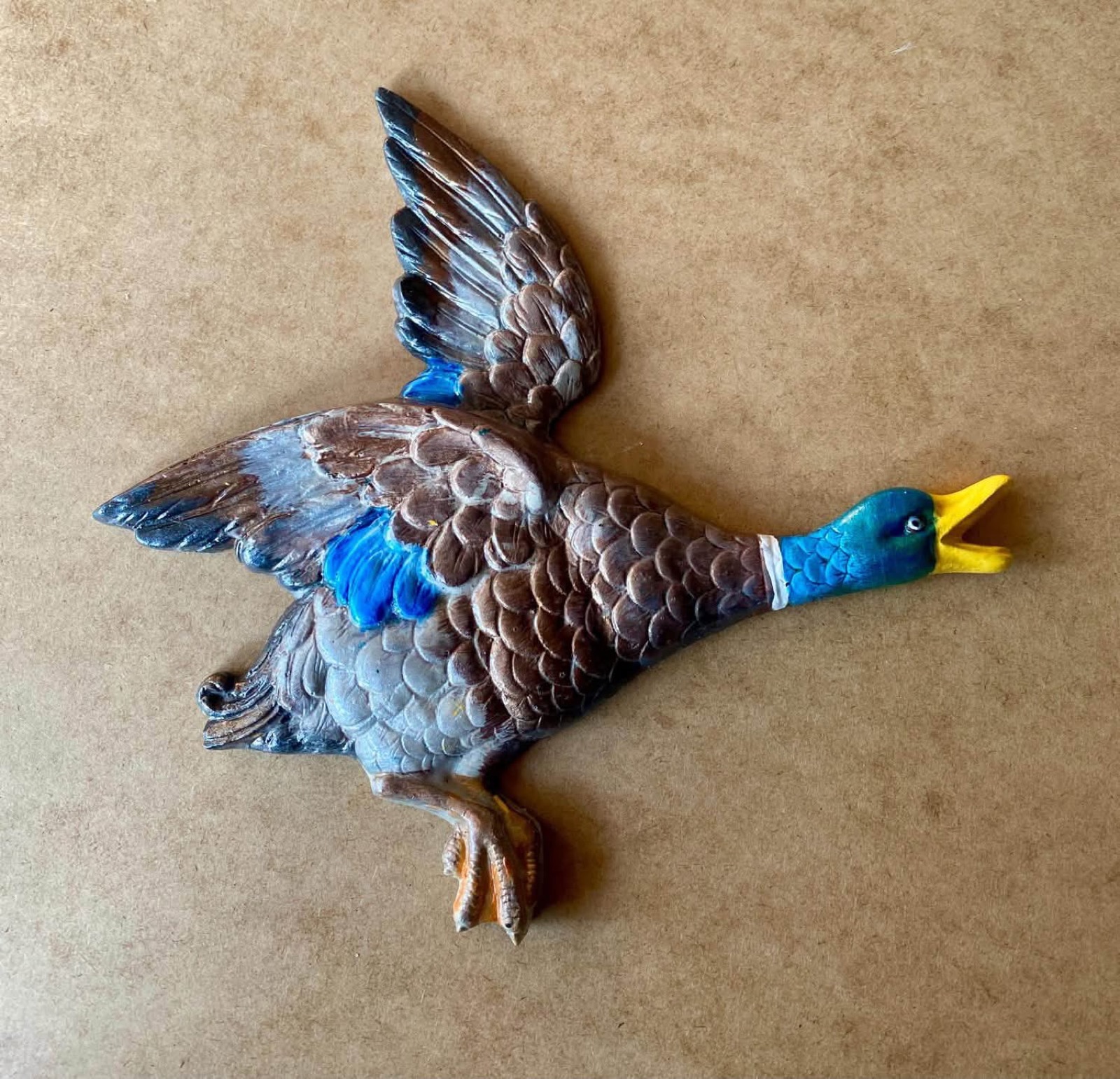 A single flying duck painted in naturalistic brown, grey and blue