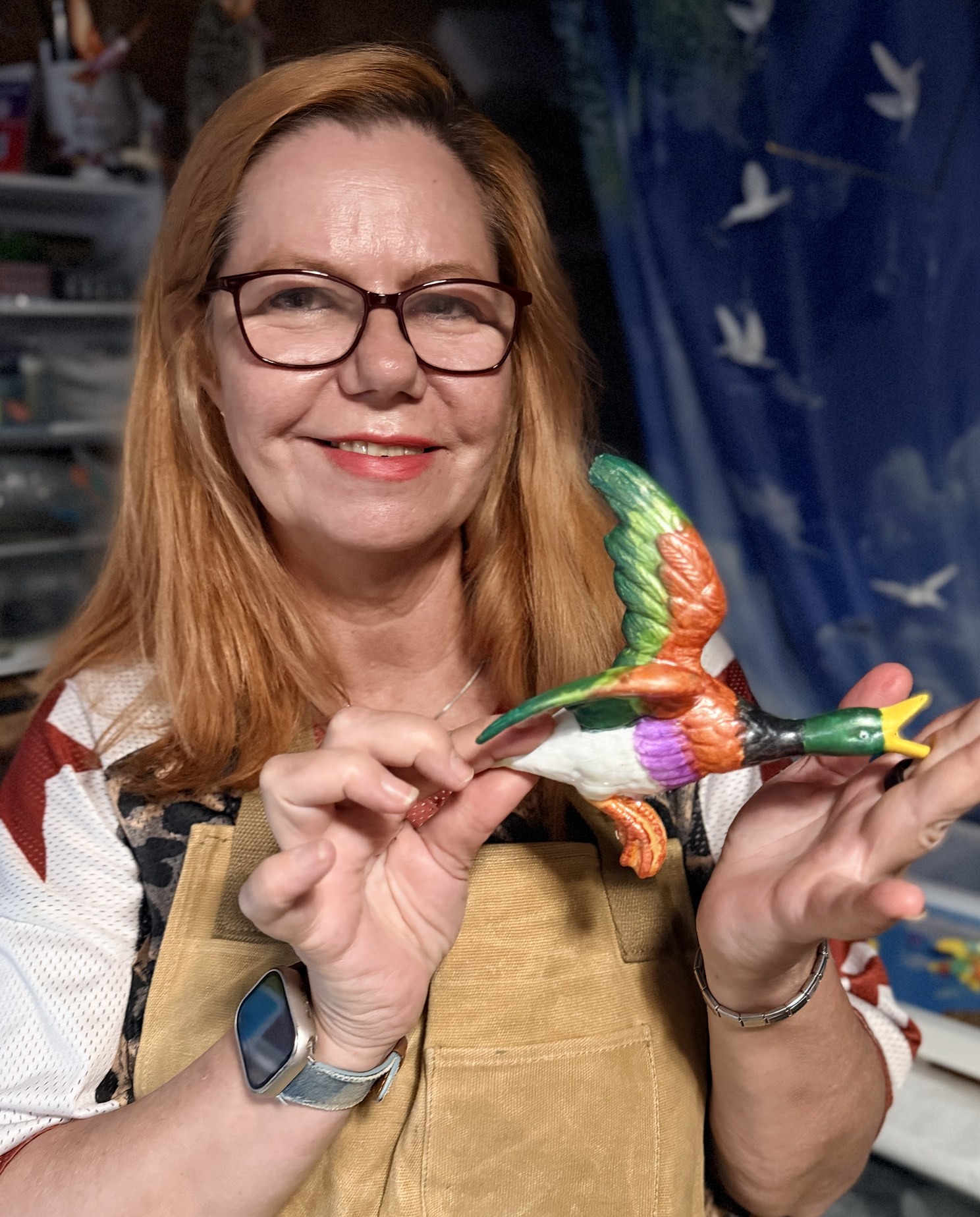 Retha in her Leigh-on-Sea workshop, holding a freshly painted green and orange flying duck